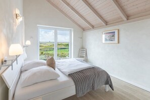 A bedroom with a bed, a window, a picture on the wall, and a lamp. - skandinavisches Reihenhaus in Dagbüll (Dagebüll)