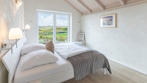 A bedroom with a bed, a window, a picture on the wall, and a lamp. - skandinavisches Reihenhaus in Dagbüll (Dagebüll)