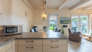 Una cocina moderna con una isla central, electrodomésticos integrados y un comedor con sillas.