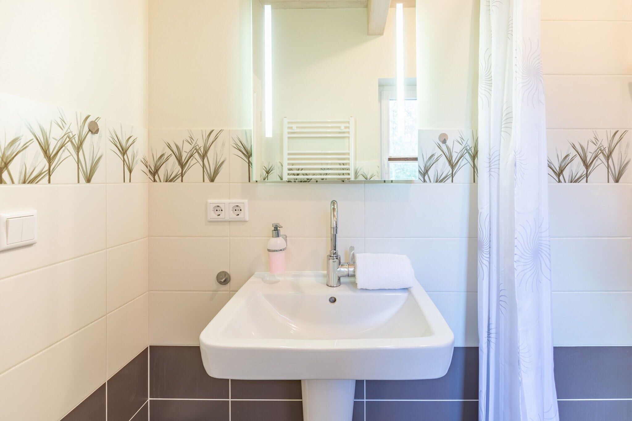 A bathroom with a white sink, a mirror, a towel, and a shower curtain.