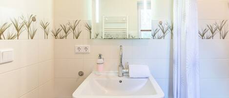 A bathroom with a white sink, a mirror, a towel, and a shower curtain.