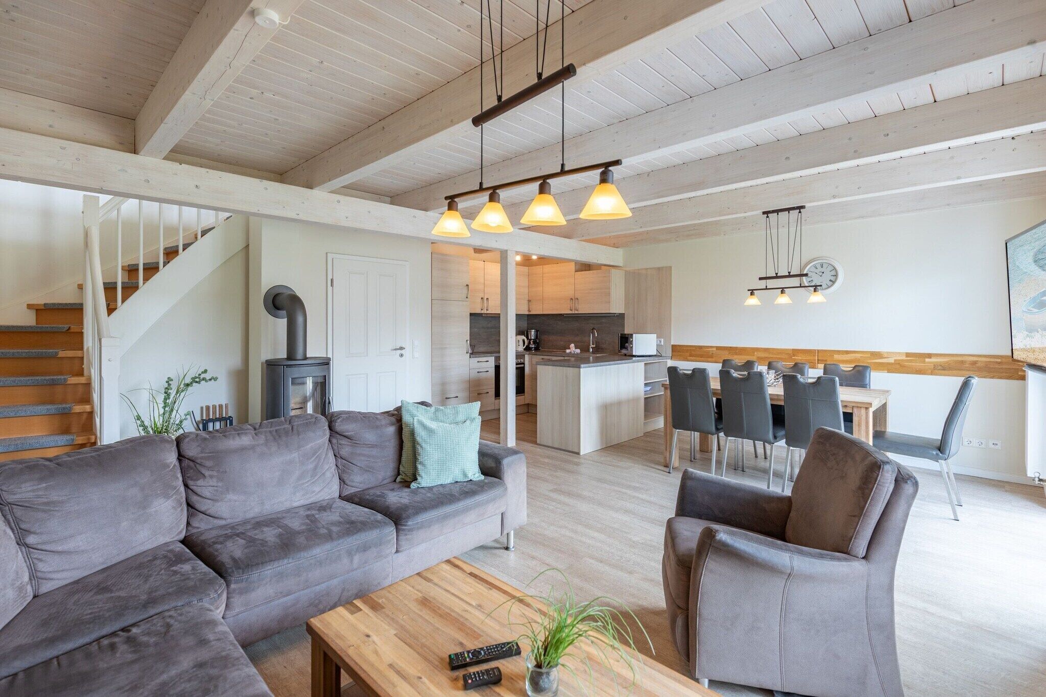 Ein modernes Wohnzimmer mit Sofa, Sessel und Couchtisch. Eine Treppe führt auf eine höhere Ebene.