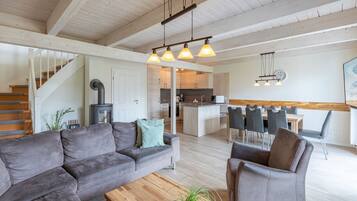 Ein modernes Wohnzimmer mit Sofa, Sessel und Couchtisch. Eine Treppe führt auf eine höhere Ebene.