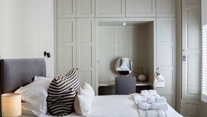 Een slaapkamer met een bed, een bedlampje en een spiegel.