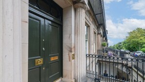 A building with a green double door, a stone facade, and a black wrought iron fence. - Luxury Georgian Terrace, with superb views of  Arthur`s seat (Edinburgh)