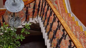 A staircase with a wooden handrail, patterned carpet, and a hanging light fixture. - Luxury Georgian Terrace, with superb views of  Arthur`s seat (Edinburgh)
