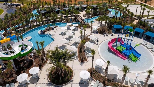 A resort with a large swimming pool, water slides, and lounge areas with umbrellas. - Magic Dream Home (clermont)