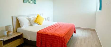 A neatly arranged bedroom with a bed, bedside table, and a wall-mounted air conditioner.