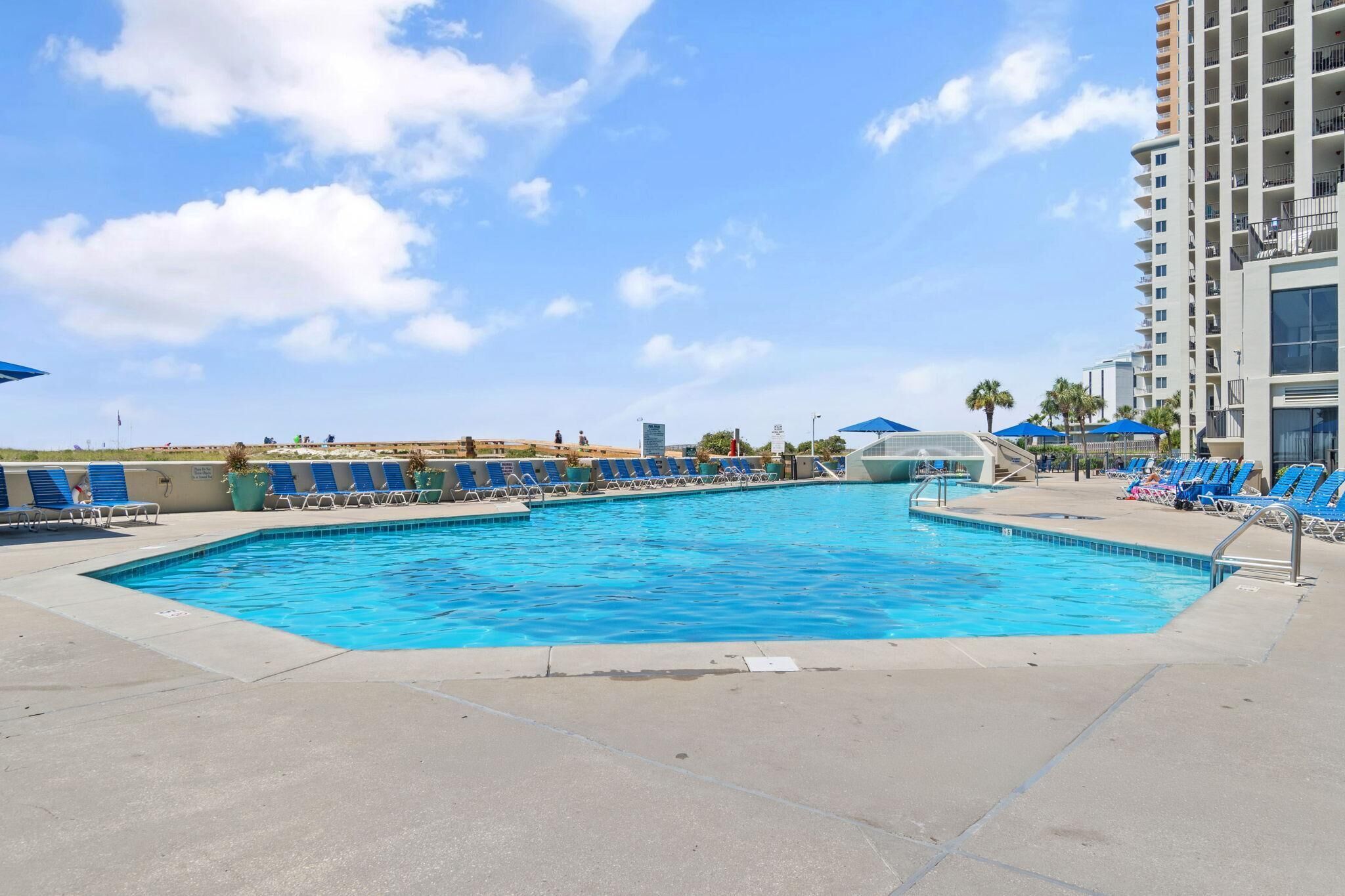 Une piscine à l’eau bleue, entourée de chaises longues et de parasols.