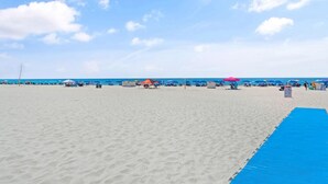 A beach with umbrellas and beach chairs, a blue mat, and a clear sky. - Phoenix 6 011 (Orange Beach)