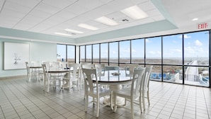 A conference room with a large table and chairs, large windows with a view of the landscape, and an exit sign on the ceiling. - Phoenix 6 011 (Orange Beach)