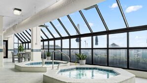 An indoor swimming pool area with two pools, large windows, and a seating area with chairs and tables. - Phoenix 6 011 (Orange Beach)