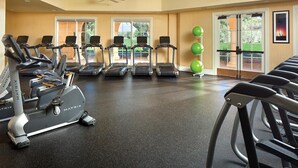 A gym with treadmills, stationary bikes, and exercise balls.