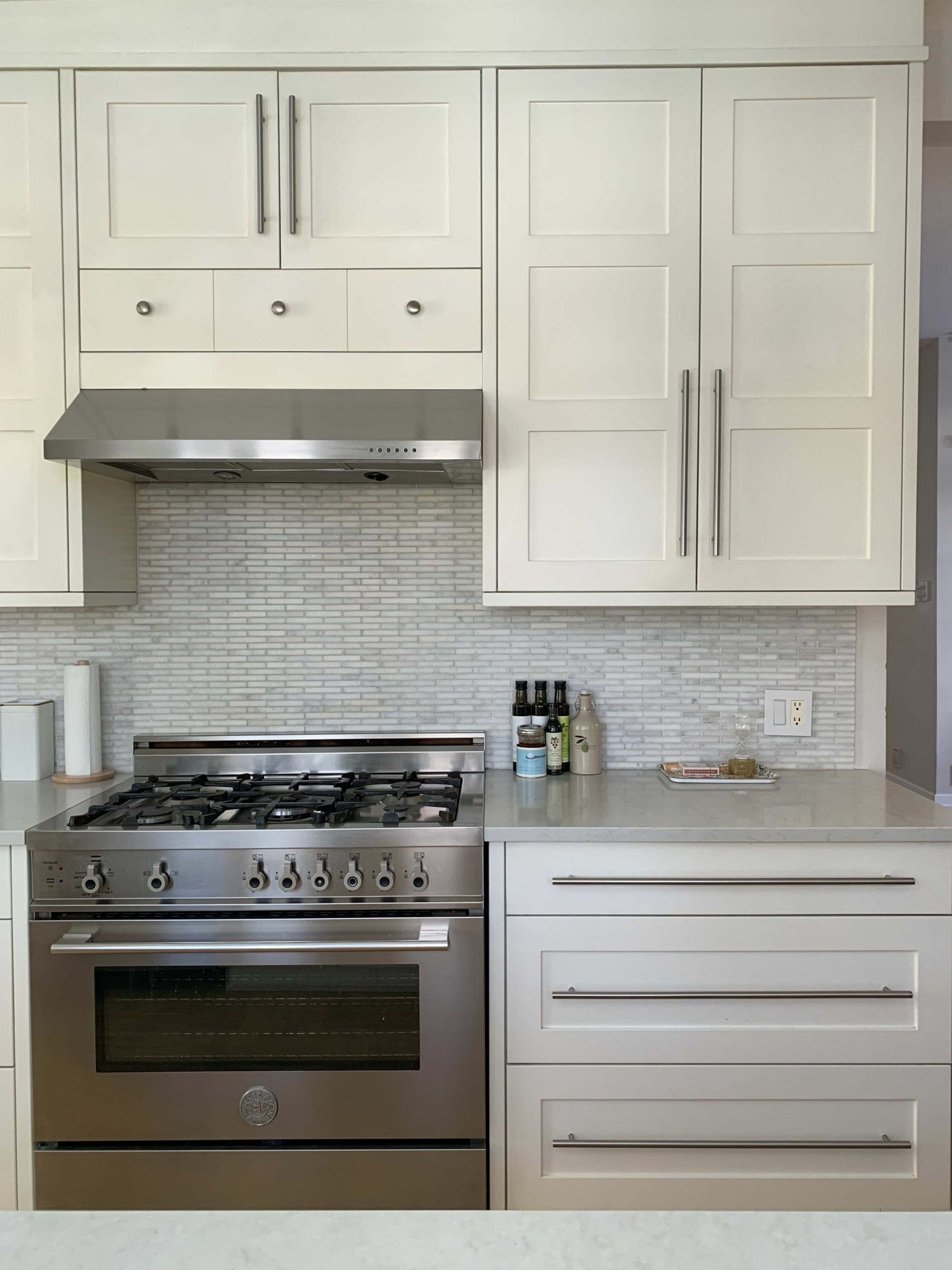 A kitchen with white cabinets, a stainless steel stove, and a tiled backsplash.
