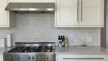 A kitchen with white cabinets, a stainless steel stove, and a tiled backsplash.