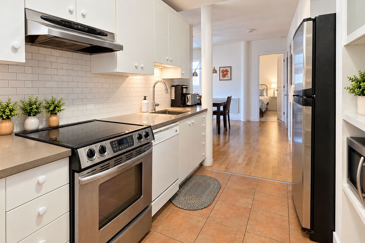 Una cocina moderna con armarios blancos, una estufa de acero inoxidable y un refrigerador negro.