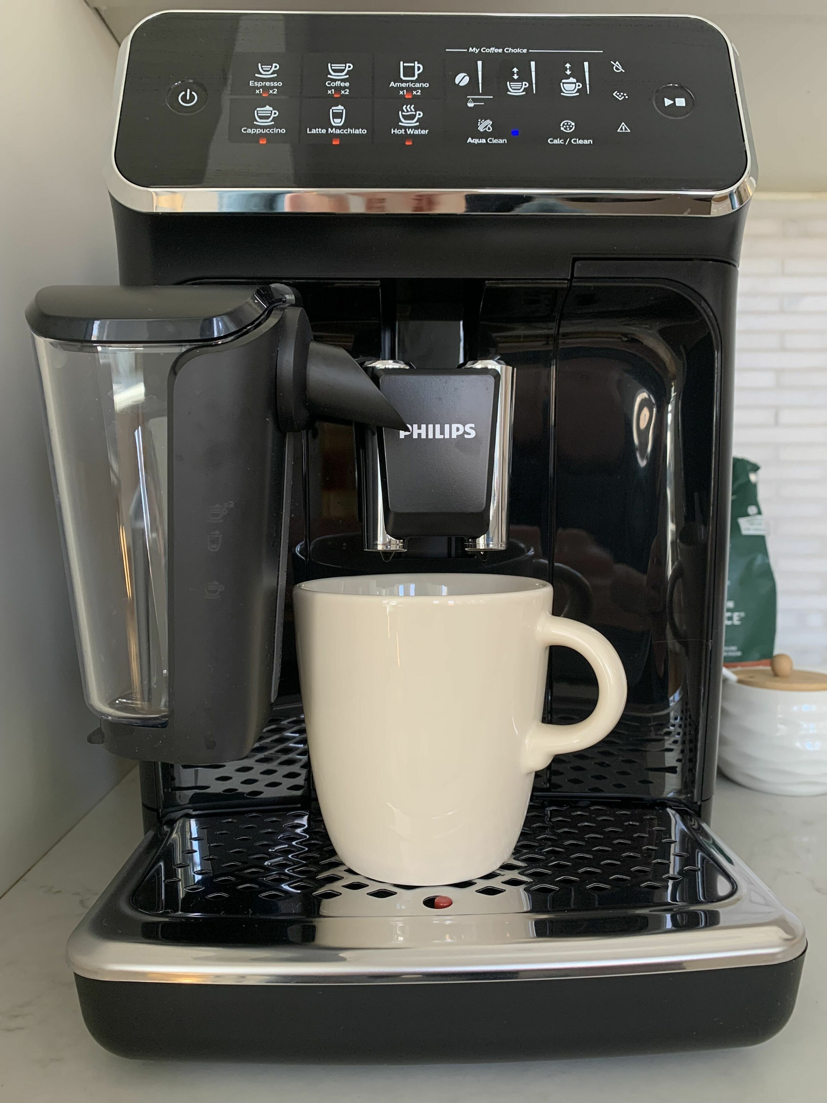 Een koffiezetapparaat met een bekerhouder, een aan/uit-knop en een digitaal scherm.