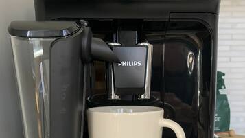 Een koffiezetapparaat met een bekerhouder, een aan/uit-knop en een digitaal scherm.