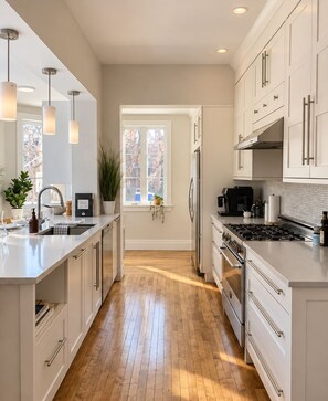 Una cocina moderna con armarios blancos, una isla central y vistas al exterior.
