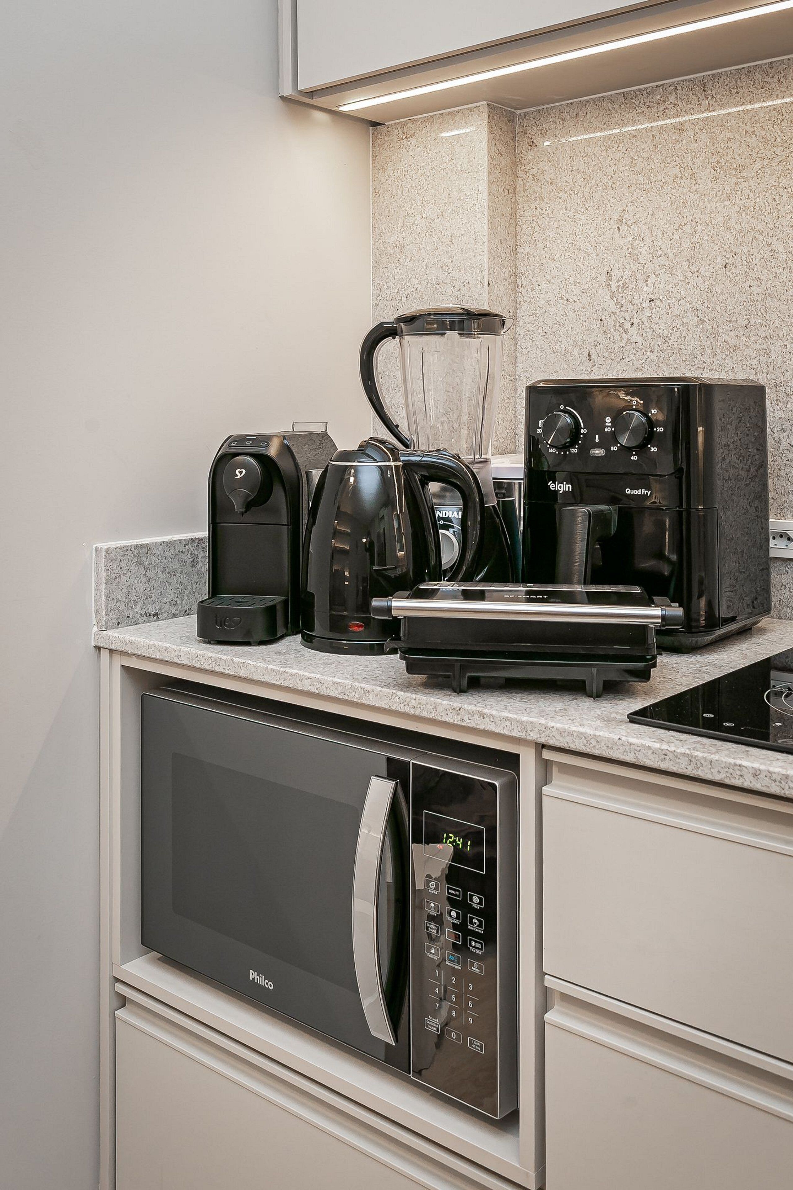 A modern kitchen with a built-in microwave, coffee maker, and toaster.