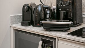 Een moderne keuken met een ingebouwde magnetron, koffiezetapparaat en broodrooster.