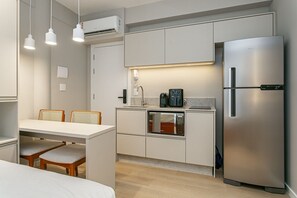 Eine kompakte Küche mit Einbau-Mikrowelle, Kühlschrank sowie einem Essbereich mit Tisch und Stühlen.