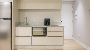 Eine kleine Küche mit Backofen, Kaffeemaschine und Kühlschrank.