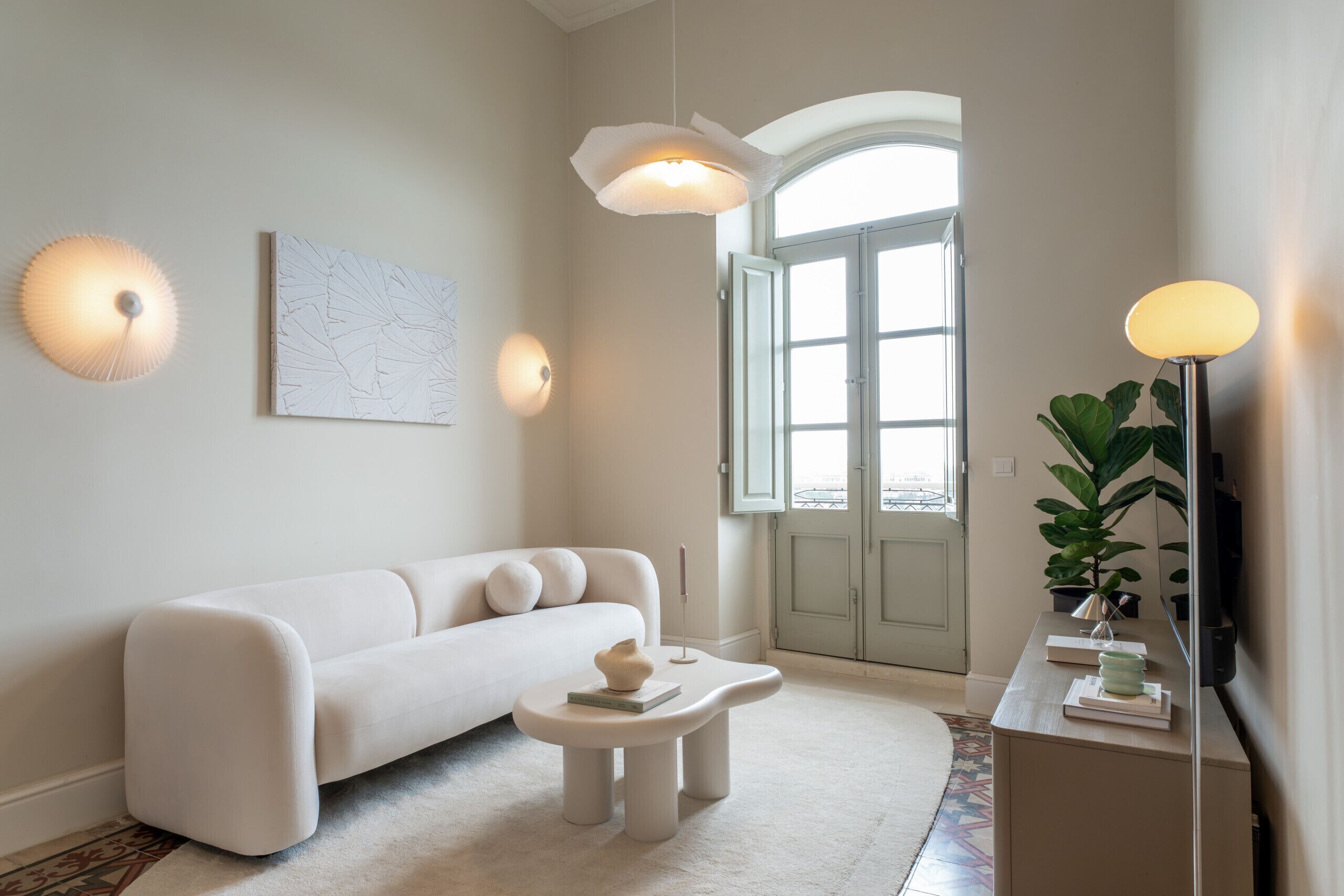A modern living room with a white sofa, a small round table, and a floor lamp.
