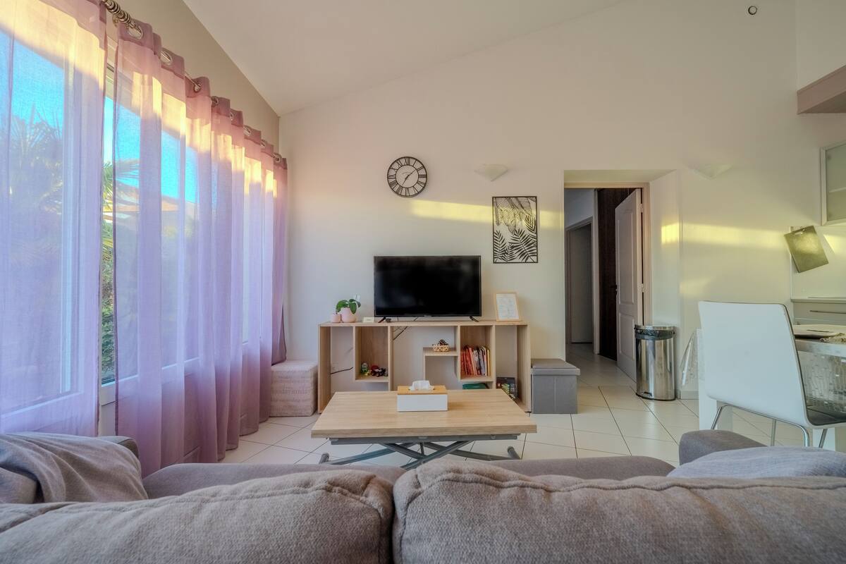 A living room with a sofa, a coffee table, a TV, and a bookshelf.