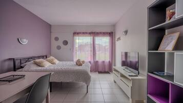 A bedroom with a bed, a desk, a TV, and a bookshelf.
