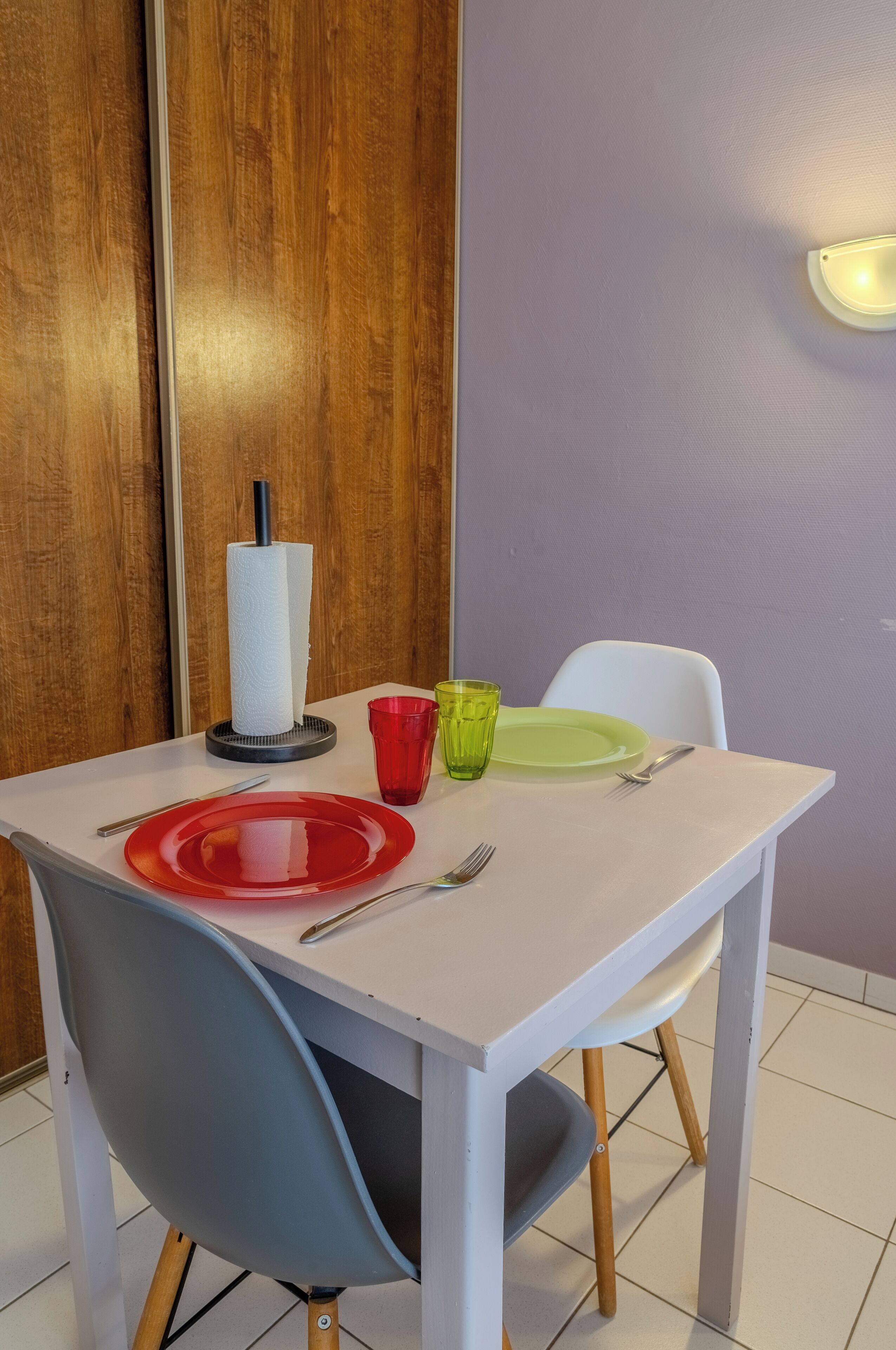 A dining table with a white tablecloth, two chairs, and a paper towel holder.