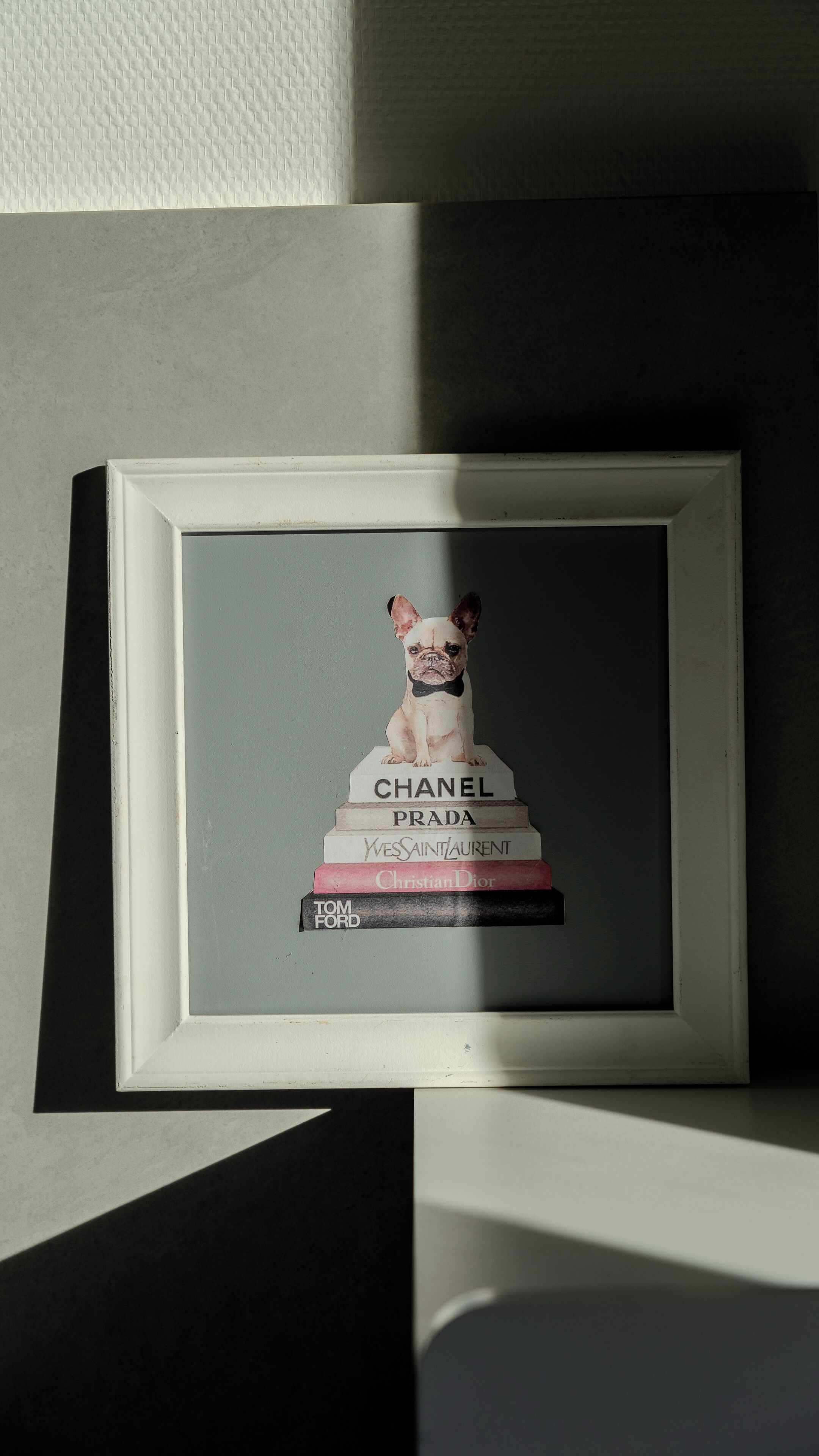 A framed sculpture of a dog on a pedestal with brand names.