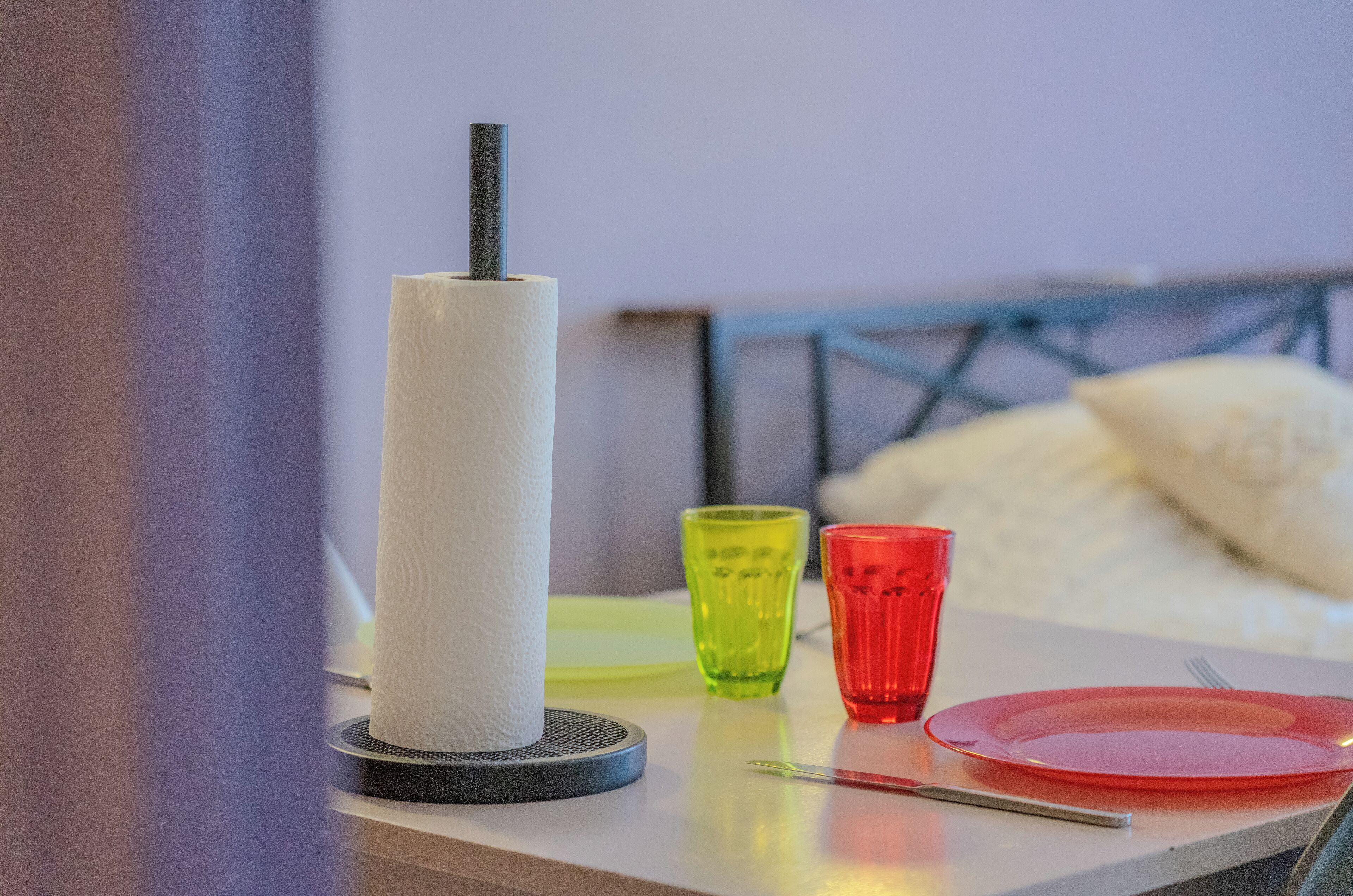 A neatly arranged table with a tissue roll, two glasses, and a red plate.