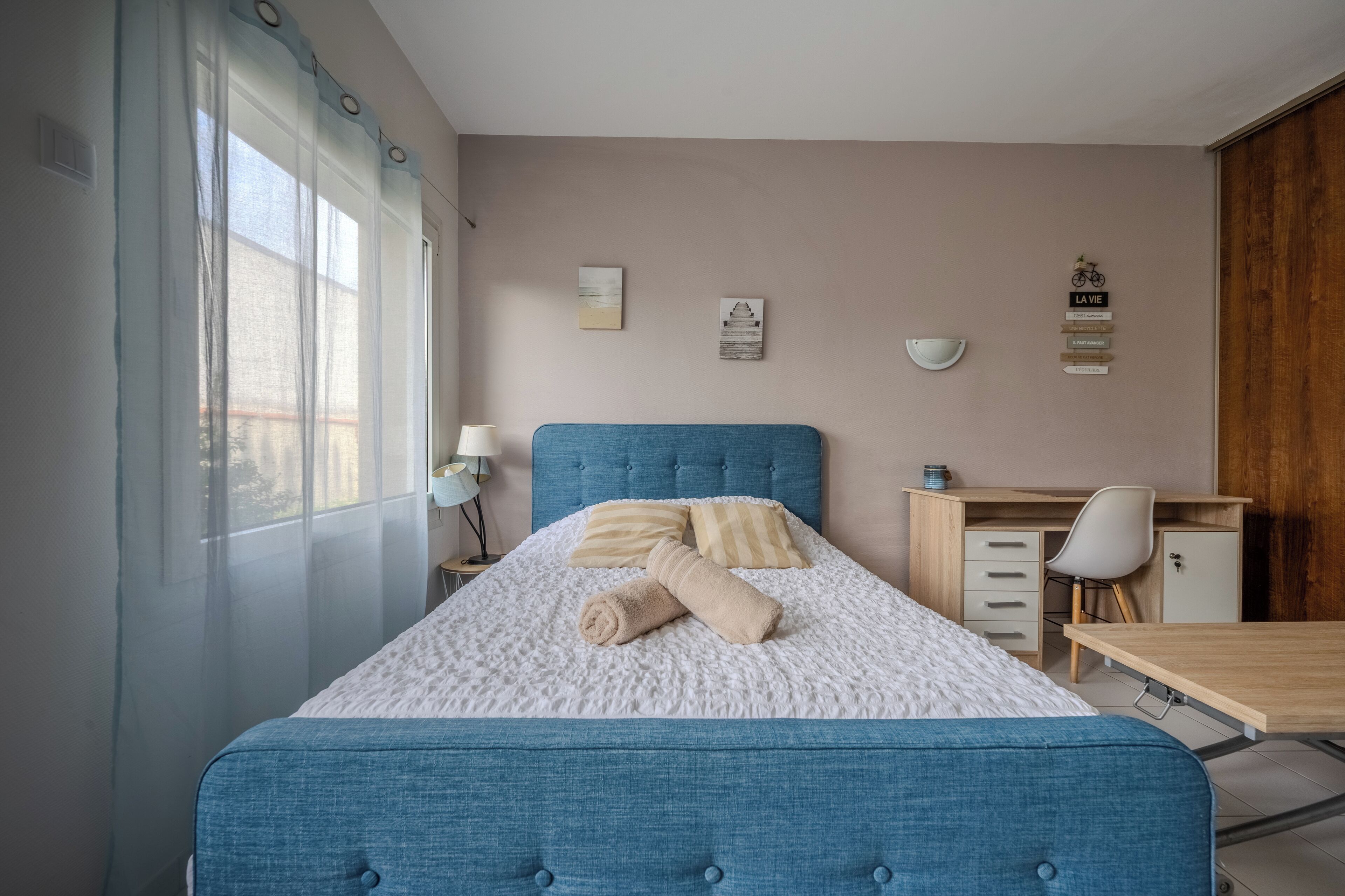 Ein ordentlich eingerichtetes Schlafzimmer mit einem großen Bett, einem Schreibtisch und einem Stuhl.