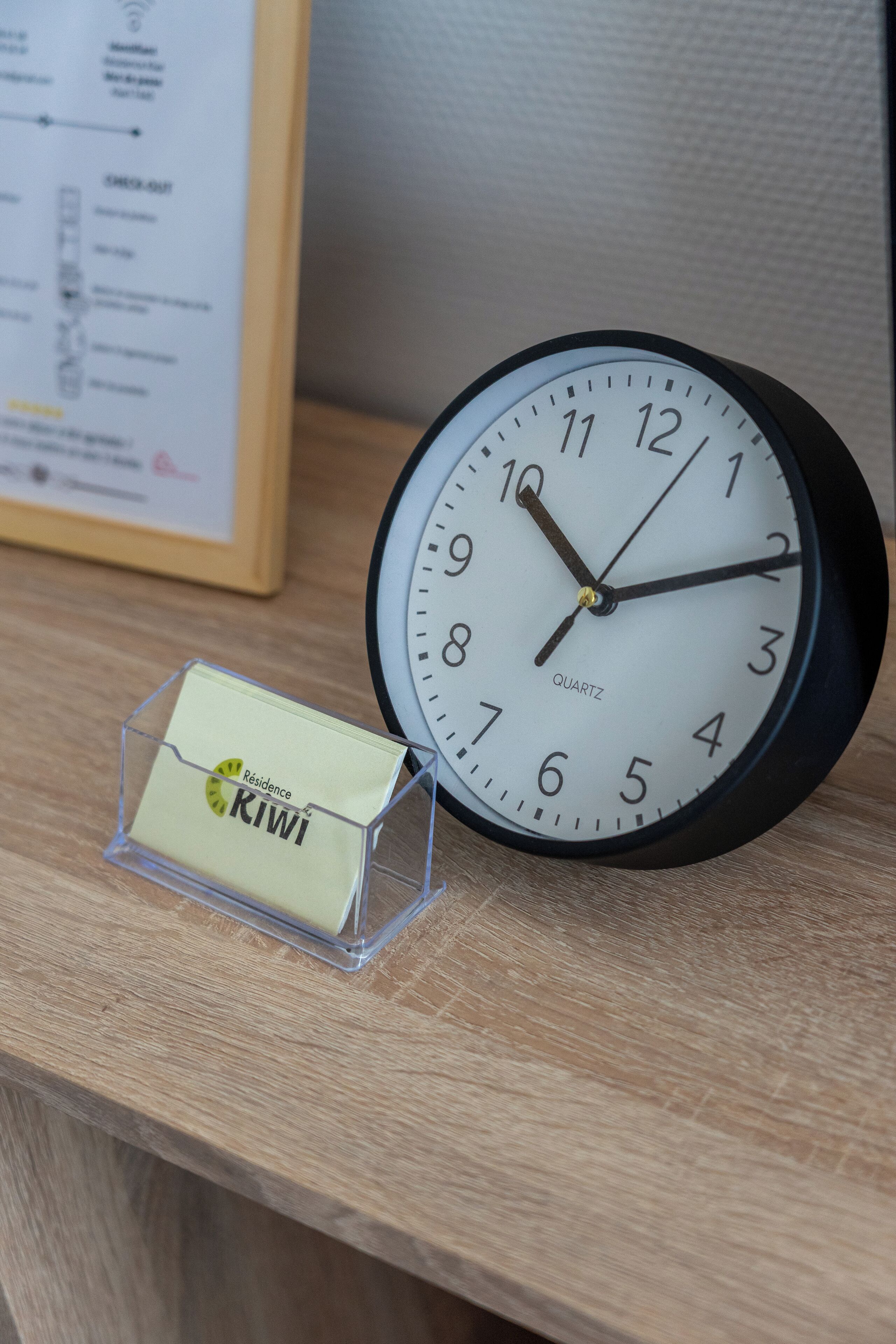 A clock with a black frame and white face, displaying the time as 10:10.