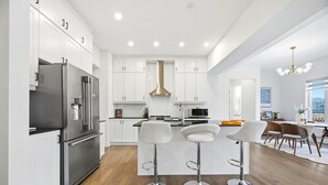 A modern kitchen with white cabinets, stainless steel appliances, and a central island with bar stools.