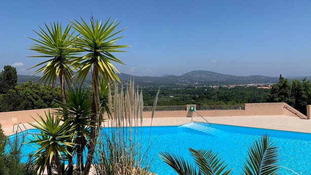 Ein Schwimmbecken mit Blick auf eine Stadt und Berge im Hintergrund.
