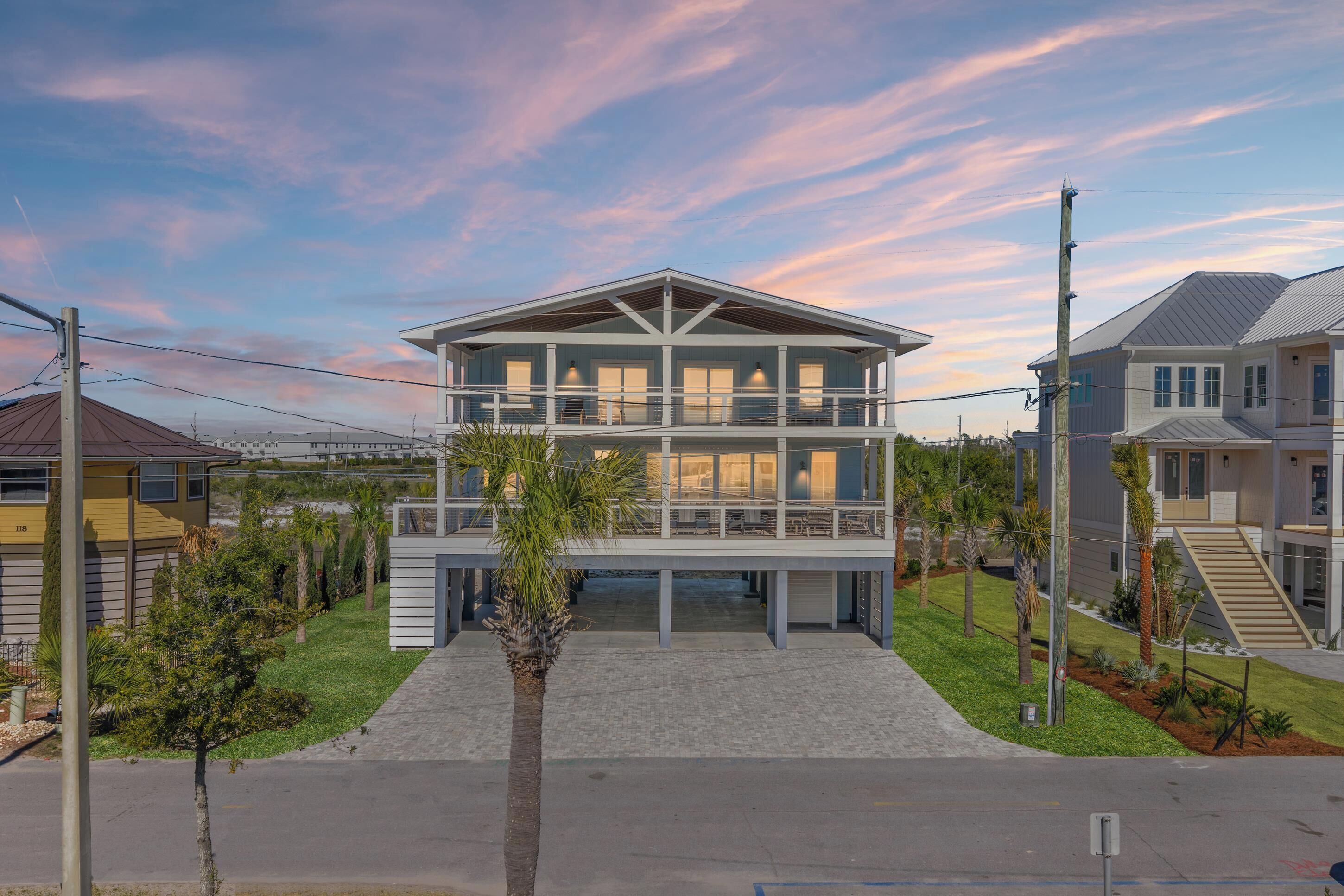 A two-story house with a balcony, a driveway, and a clear sky.