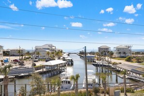Uma marina com barcos atracados, um cais que se estende sobre a água e edifícios com vista para o mar.