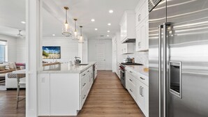 Una cocina moderna con armarios blancos, electrodomésticos de acero inoxidable y piso de madera.