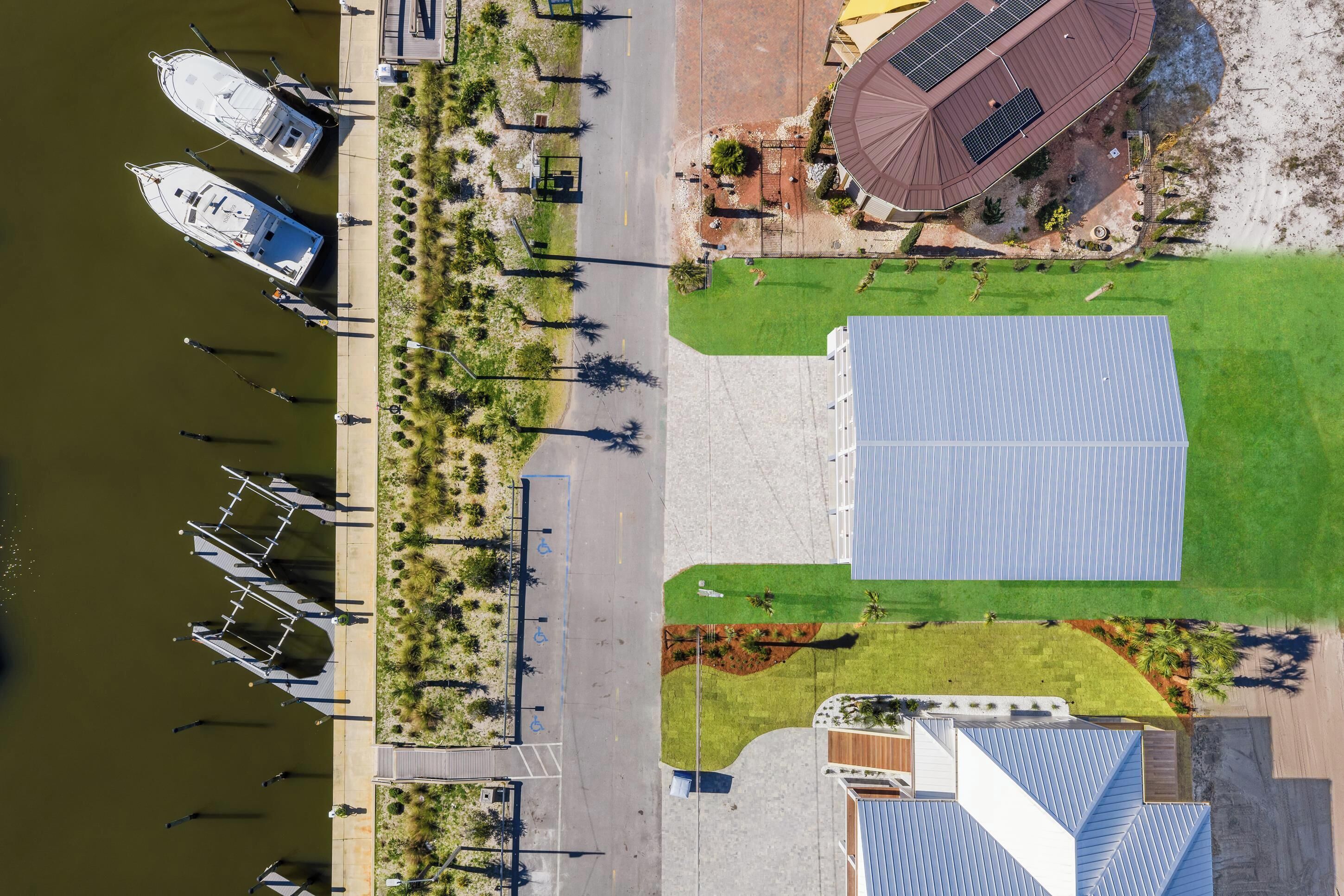 An aerial view of a marina with boats docked, a pedestrian walkway, and a building with solar panels.
