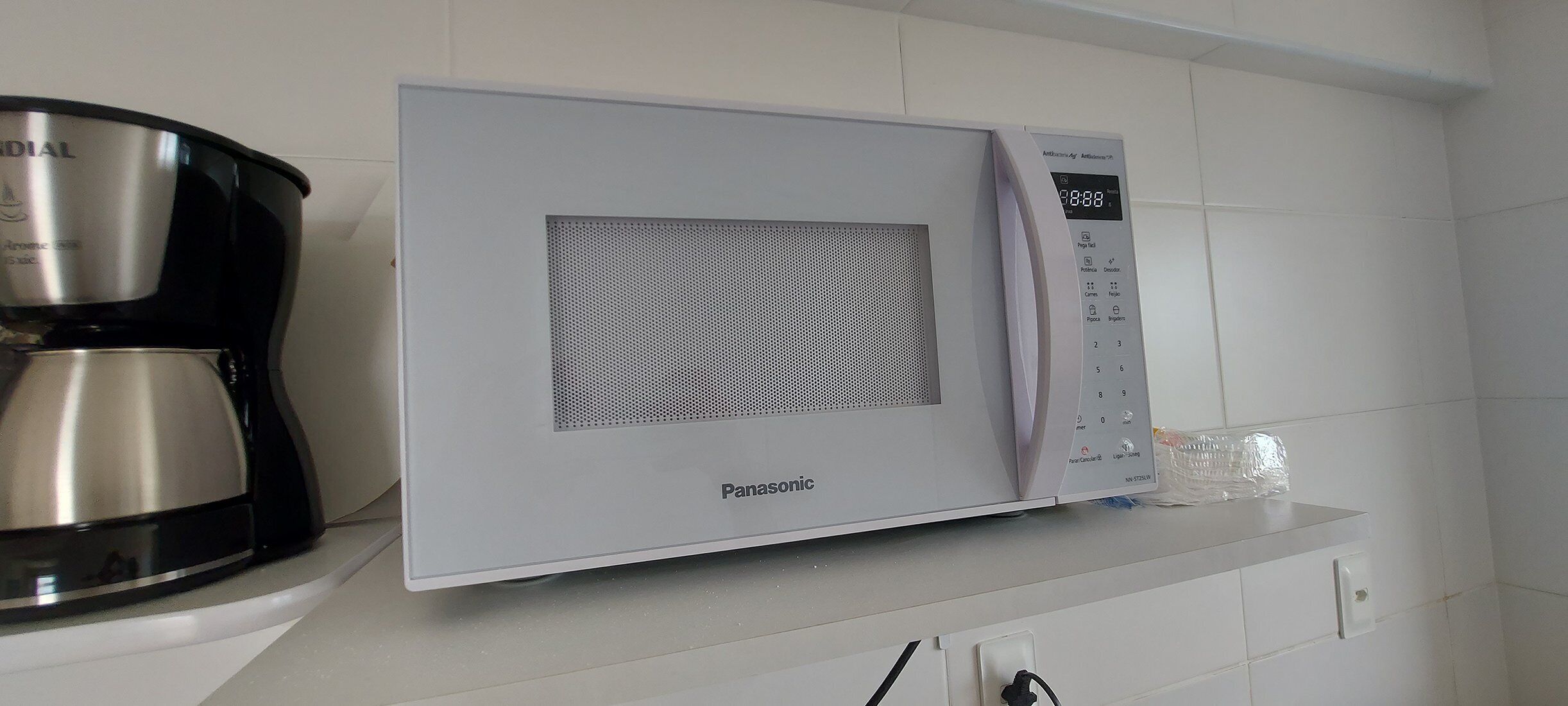 A Panasonic microwave oven on a white tiled kitchen counter.