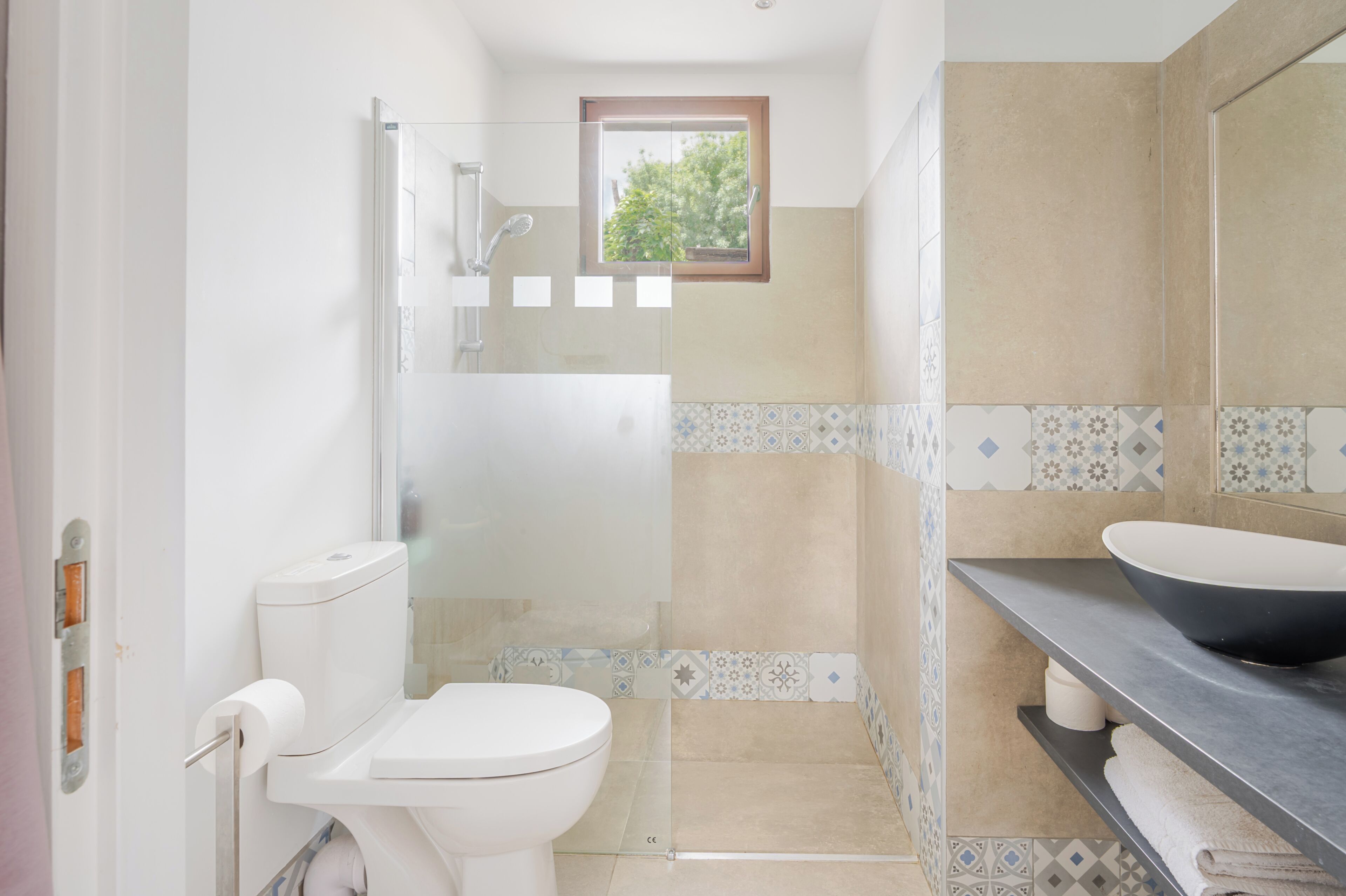 Un baño con inodoro, ducha, lavabo y ventana.