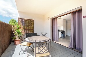 Un balcone con un tavolo rotondo e sedie, una pianta in vaso e un recinto in legno.
