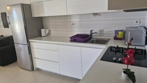 A modern kitchen with white cabinets, a stainless steel refrigerator, a sink, and a small countertop with a vase of flowers. - Apartment Slanica Beach Escape (Murter-Kornati)