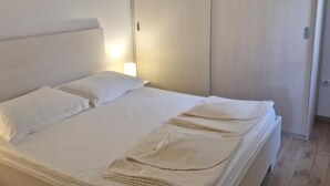 A neatly made bed with white linens and a folded towel. - Apartment Slanica Beach Escape (Murter-Kornati)