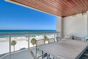 Un balcon donnant sur une plage, avec une table et des chaises.
