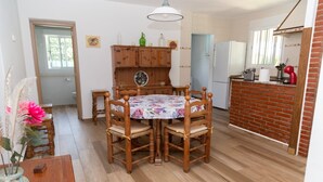 Ein Essbereich mit einem runden Holztisch, Stühlen, einer Kommode und einer Küchenzeile mit Backsteinwand und Kühlschrank.