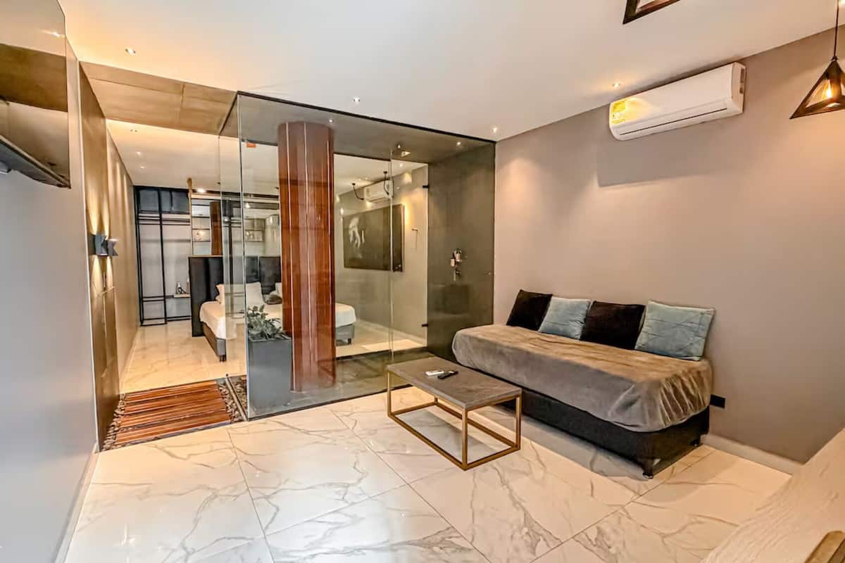 A modern living room with a glass partition, a sofa, a coffee table, and a minimalist design.