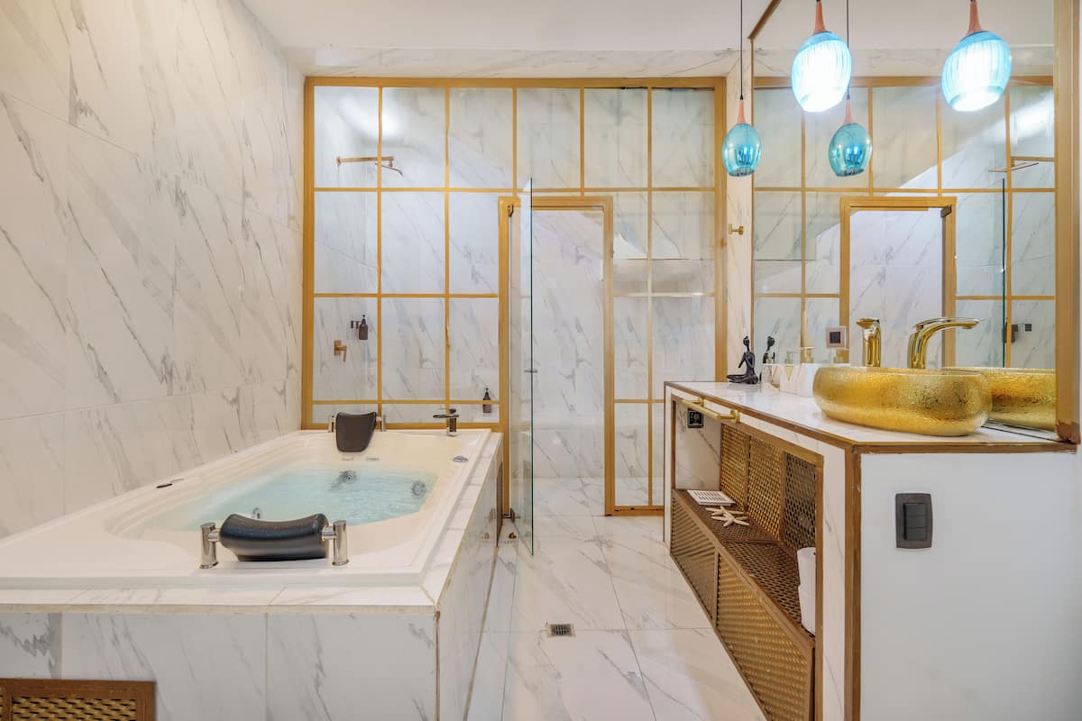 A modern bathroom with a large bathtub, a glass-enclosed shower, and a vanity with a large mirror and a yellow sink.